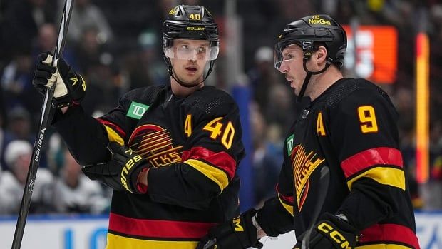 Elias Pettersson of the Vancouver Canucks listens to teammate and fellow forward J.T. Miller before a faceoff during a November 20, 2023 NHL regular-season game against the visiting San Jose Sharks. 