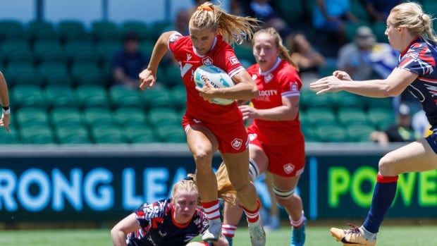 A female rugby player runs the ball.