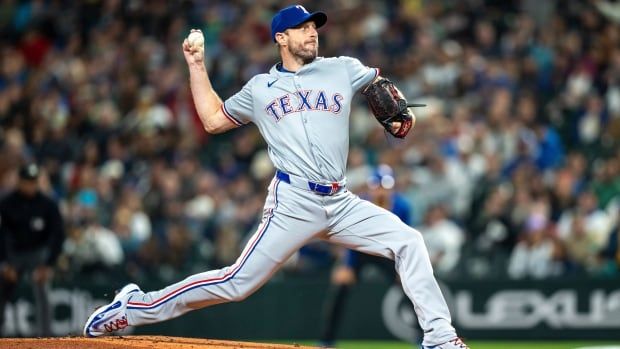 A male baseball pitcher delivers a pitch.