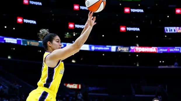 A female basketball player takes a shot.