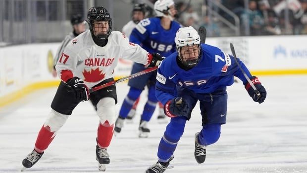 A Canadian player skates behind an American player on the ice.