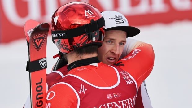 Two men's skiers hug.