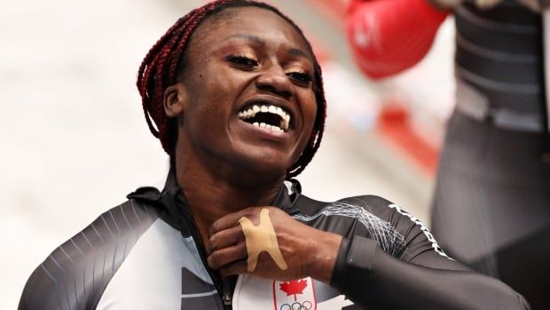 A women's bobsleigh athlete is shown smiling, and has a bandage on her hand.