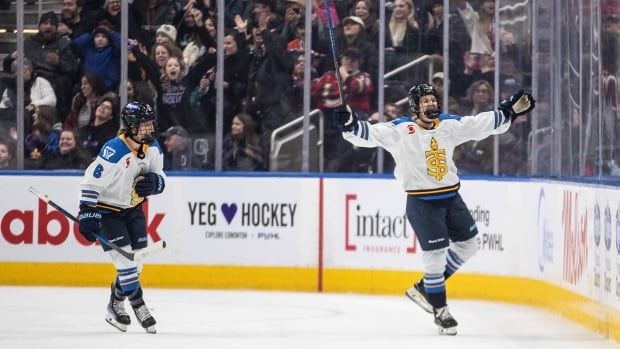 Two women's hockey players celebrate after a game-winning goal.