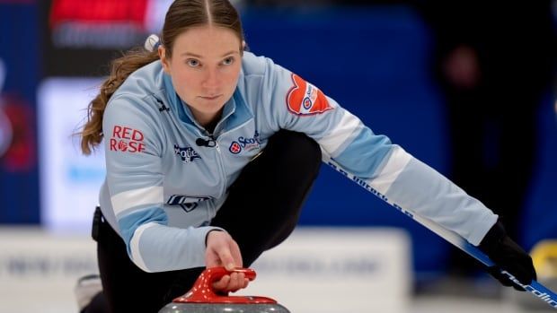 A female curling skip delivers a stone with her right hand.