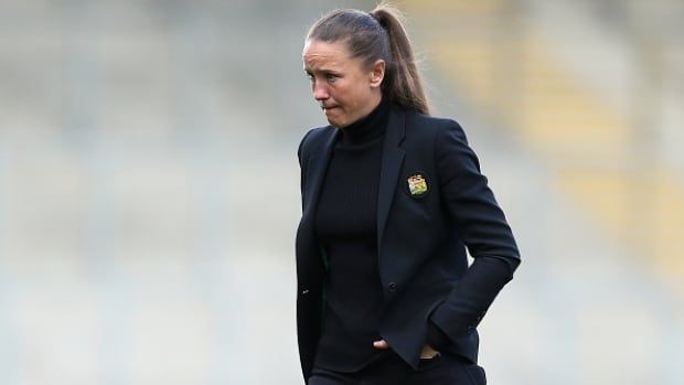 A female soccer coach walks on the field.