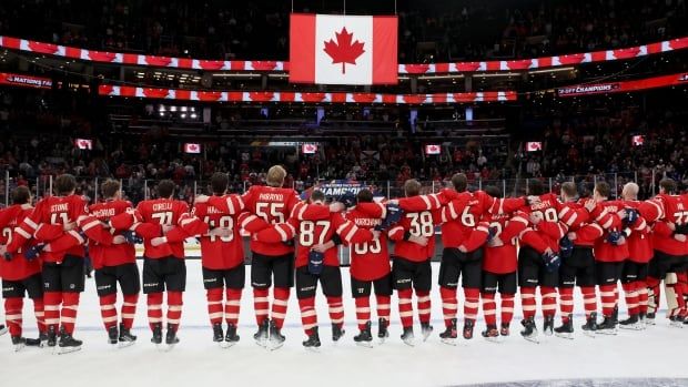 Team Canada on the ice in front of a large Canada flag.