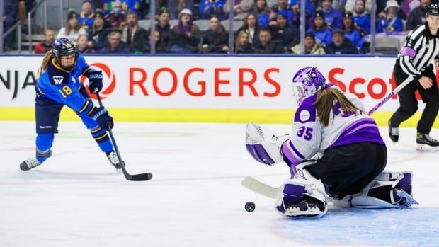 A women's hockey player shoots on a goaltender during a game.