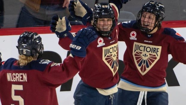 Three women's hockey players celebrate.