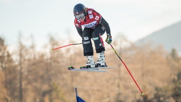 A women's ski cross athlete is shown gliding through the air.