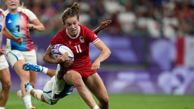 A women rugby player dives over the line to score a try.