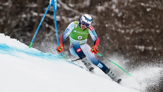 A men's alpine skier carves out a turn on a ski hill.