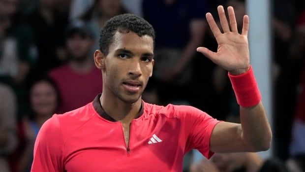 Male tennis player waves to the crowd post match.