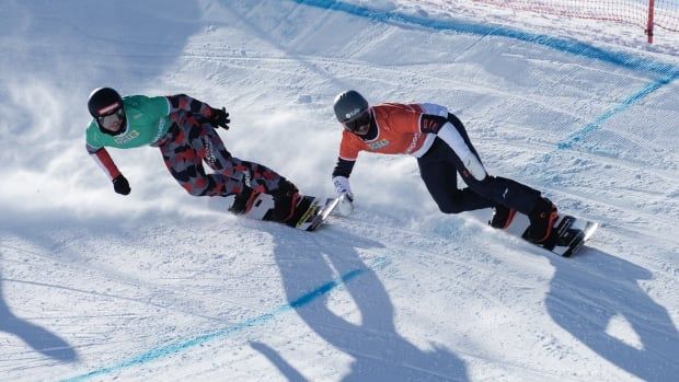 Two men's snowboarders race on a course.