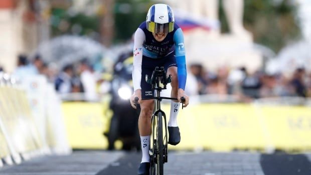 A male cyclist grits his teeth as he races down a street.