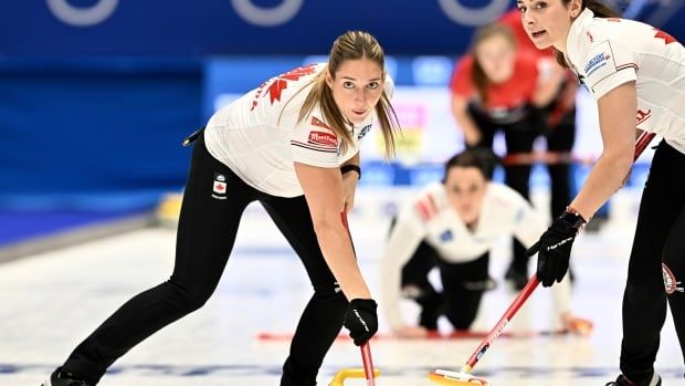 Two female curlers in action during a match.