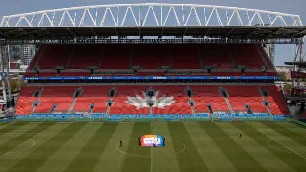 People holding a large soccer banner in the middle of an empty soccer field