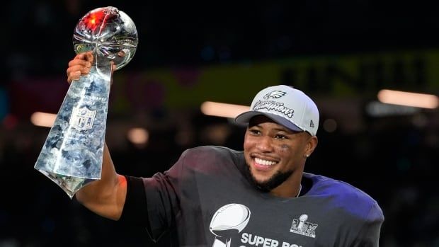 A male football player celebrates and holds a trophy.