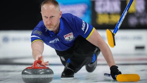 Male curler lunges down to throw rock with boom on the ice for balance.