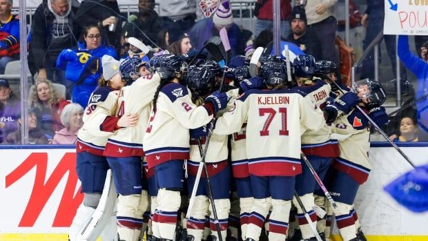 A group of hockey players celebrate on the ice.