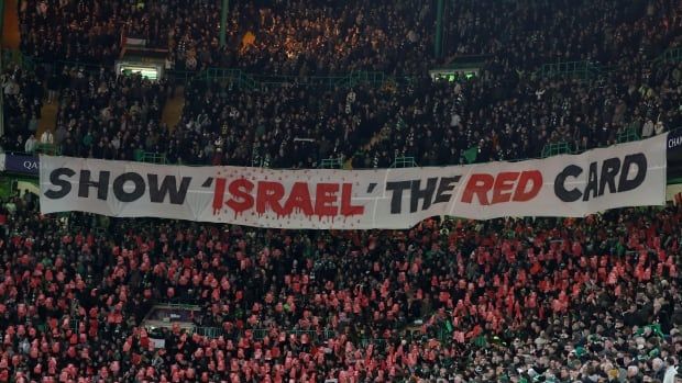 Fans hold a white banner reading "Show Israel the red card."