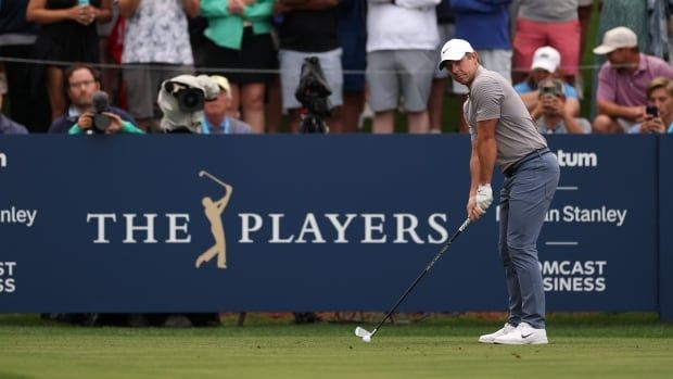 A men's golfer stand over a tee shot.