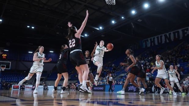 A woman's basketball player attempts a layup.