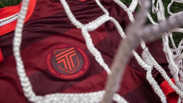 Red soccer jersey lays on soccer turf with soccer netting in front of it