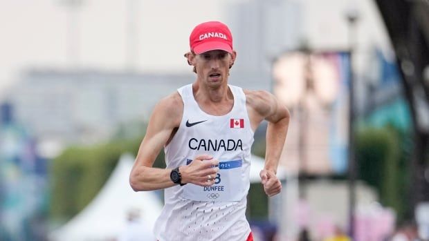 A male race walker representing Canada races outside during the day.