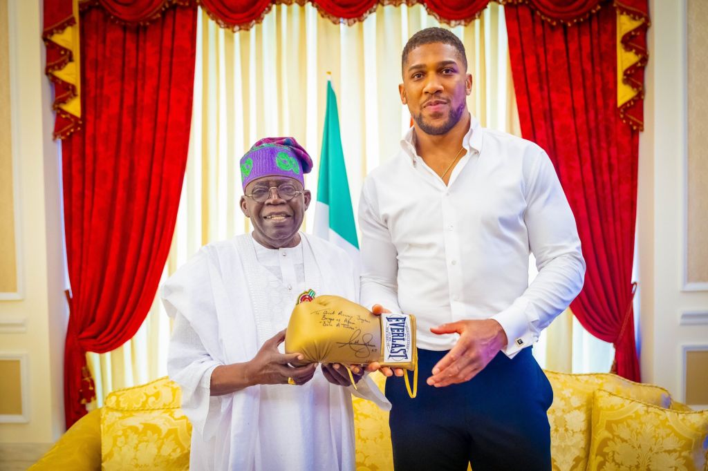 Anthony Joshua presenting President Bola Tinubu with an autographed boxing glove.