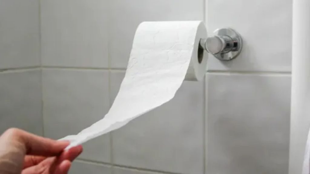 Hand tearing off a sheet of toilet paper