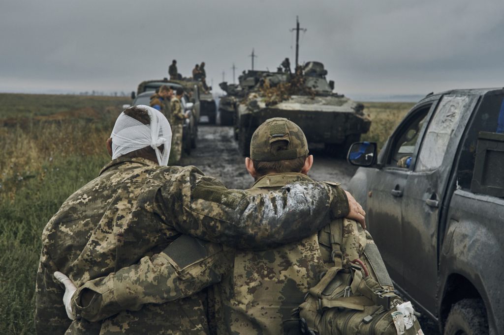 A Ukrainian soldier helps a wounded comrade on the road in reclaimed territory in the Kharkiv region, Ukraine, on Sept. 12, 2022.