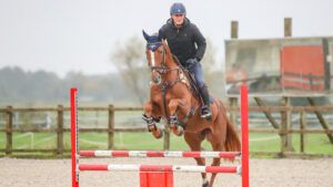 Alex Bragg training over a jump on chestnut horse