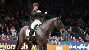 Becky Moody points at Jagerbomb with both hands as he walks on a long rein in front of the London International crowds after doing his dressage test.