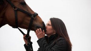 EH2T8R A young woman kissing a horses nose