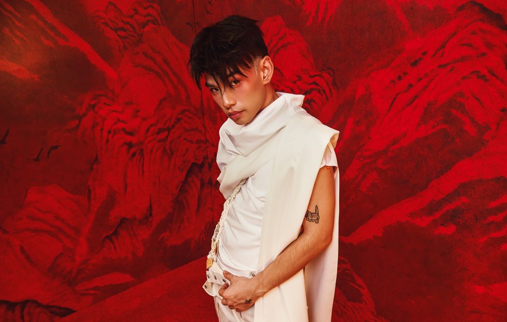 Thể Thiên photographed in a white outfit against a red background, photo by Nguyen Anh Hao