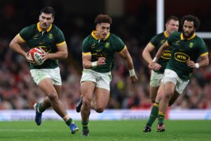 South Africa’s Damian de Allende runs with the ball, supported by Jordan and Jaden Hendrikse, during the 2024 Autumn Nations Series match against Wales.