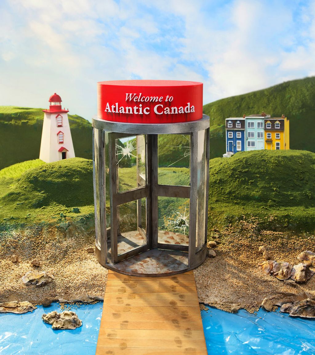 In an illustration, a boardwalk with footprints connects to a sandy shore and rolling green hills with a lighthouse and a colourful cluster of buildings. On top of a revolving door with broken windows is a sign that reads Welcome to Atlantic Canada