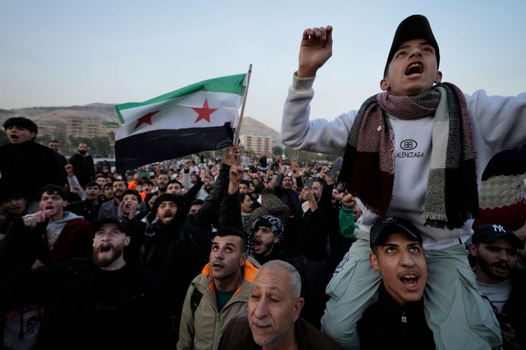 Crowds of people holding the Syrian revolutionary flag gather in celebration