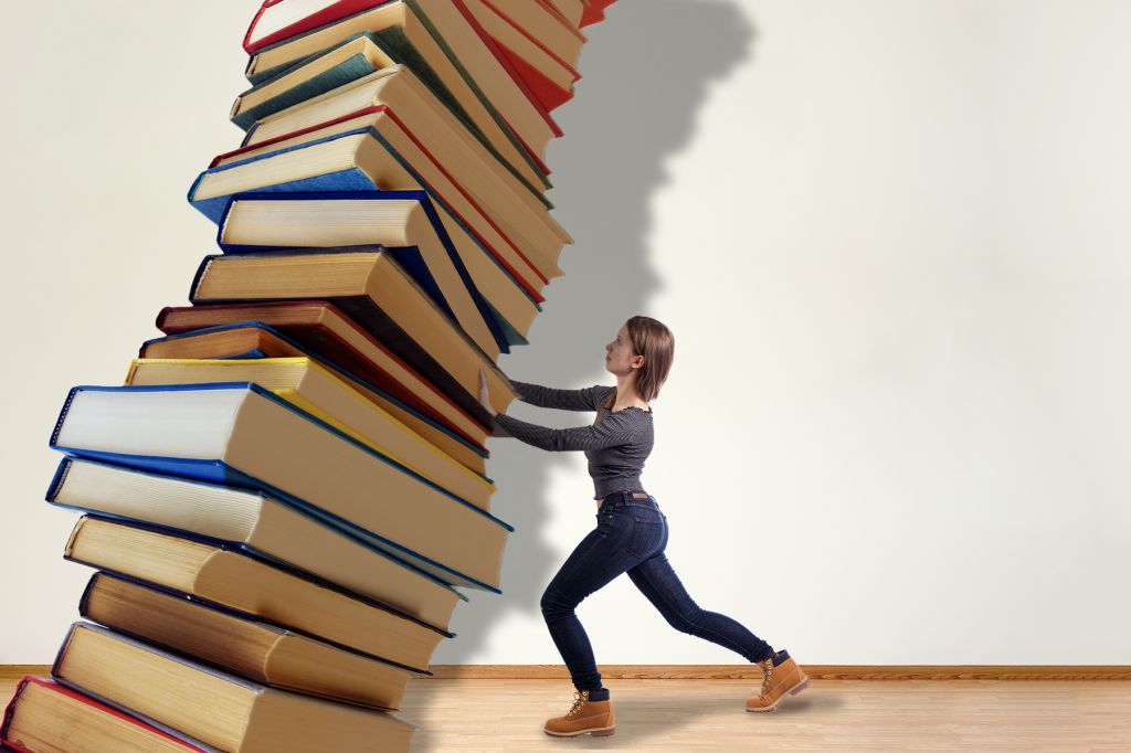 In a photo illustration, a woman tries to hold up an enormous tower of books looming and leaning over her