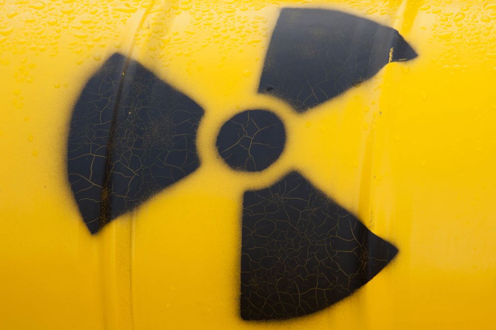 A close up photo if a black nuclear waste symbol on a yellow barrell