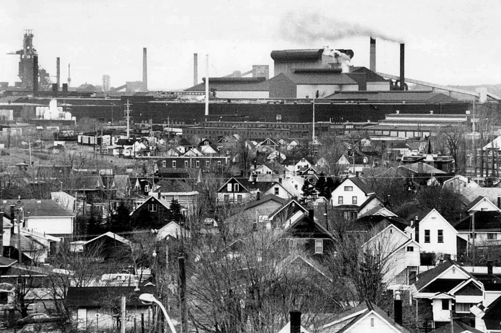 A black-and-white photo of Sault Ste. Marie, showing smokestacks above houses in winter