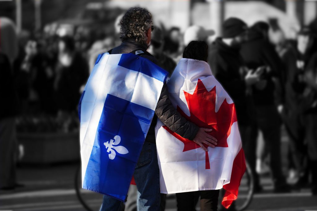 A photo of a man draped in Quebec flag putting his arm around another person draped in a Canadian flag. The background of people is blurred and in black-and-white