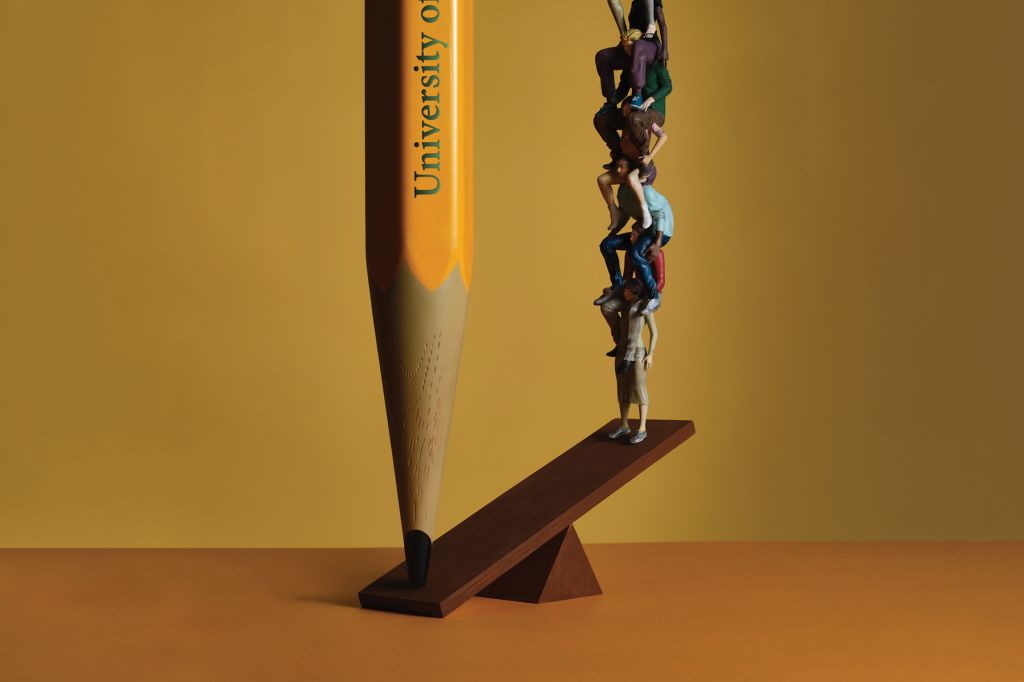 In an illustration, several people form a tower, sitting on top of each other's shoulders. They are balanced on a board against a large pencil that outweighs them. The pencil is labeled "University of"