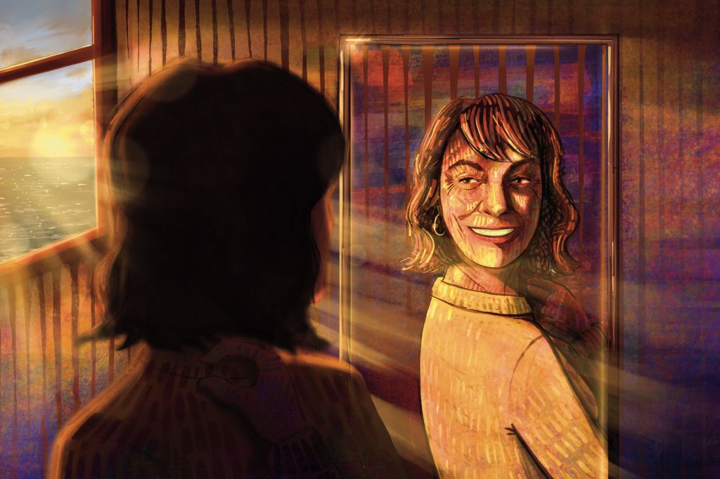 A woman smiles at her reflection in the mirror as sun from the window shines on her.