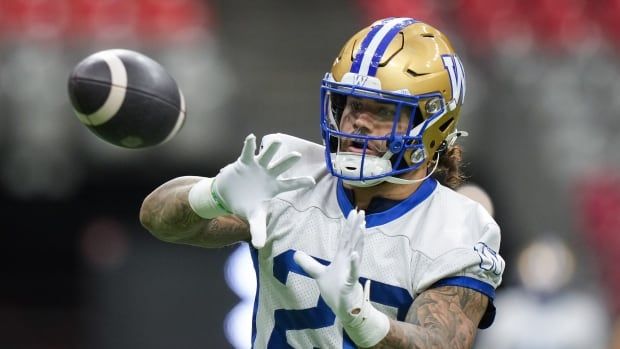 A men's football player catches a ball.