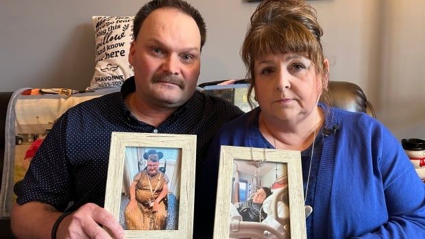 A man and a woman are shown holding photos of their daughter sitting on a couch.