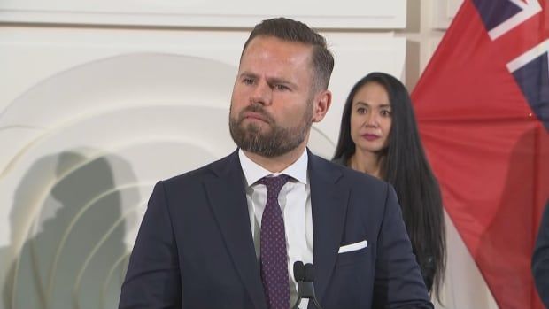 Photo of a minister in a suit speaking at a news conference