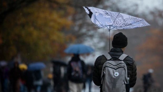 A person holds an upturned umbrella amid a period of strong wind.