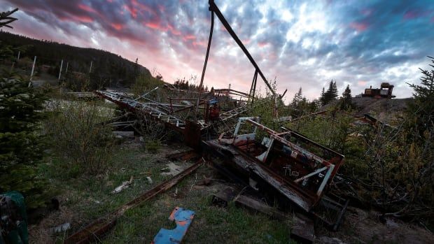 A pile of rusted and broken up beams of steel lying on the ground.